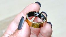 The Samsung Galaxy Ring in a user's hand with blue painted fingernails