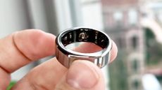 Oura Ring Gen 3 smart ring held between a person's fingers